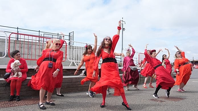 Több száz, pirosba öltözött rajongó újrajátssza Kate Bush „Üvöltő szelek” táncát