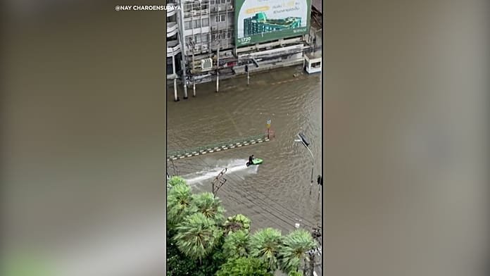 Jetskis férfi járja be az árvíz sújtotta bangkoki utcákat